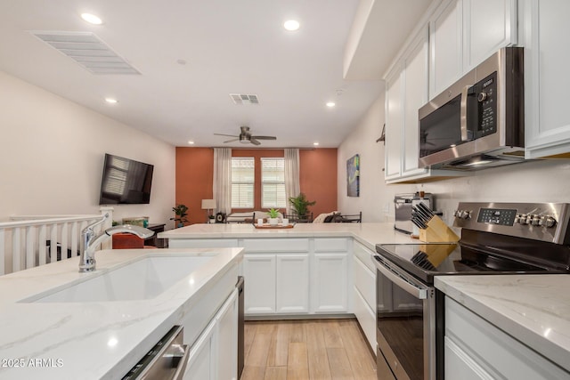 2631 S Sulley Dr Unit 106, Gilbert, AZ 85295 - kitchen with stainless steel appliances, a peninsula, light wood-style flooring, a sink, and white cabinetry
