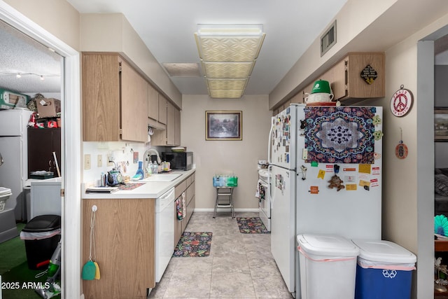 kitchen with light brown cabinetry, sink, and white appliances