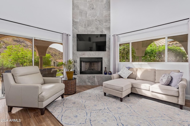 living room featuring wood-type flooring, a premium fireplace, and a high ceiling