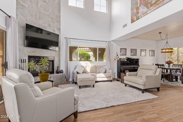 living room featuring an inviting chandelier, a healthy amount of sunlight, a fireplace, and light wood-type flooring