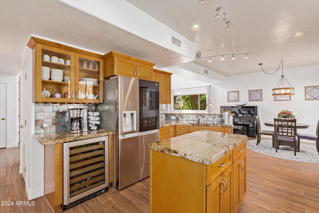 kitchen featuring wine cooler, decorative backsplash, a center island, stainless steel refrigerator with ice dispenser, and light wood-type flooring