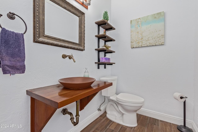 bathroom featuring wood-type flooring, toilet, and sink