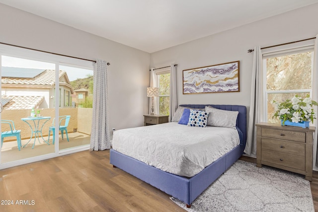 bedroom with access to outside and wood-type flooring