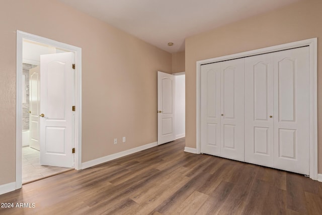 unfurnished bedroom featuring dark wood-type flooring, ensuite bath, and a closet