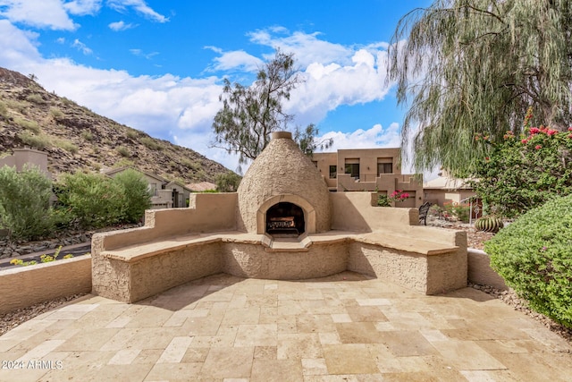 view of patio with a mountain view and an outdoor stone fireplace