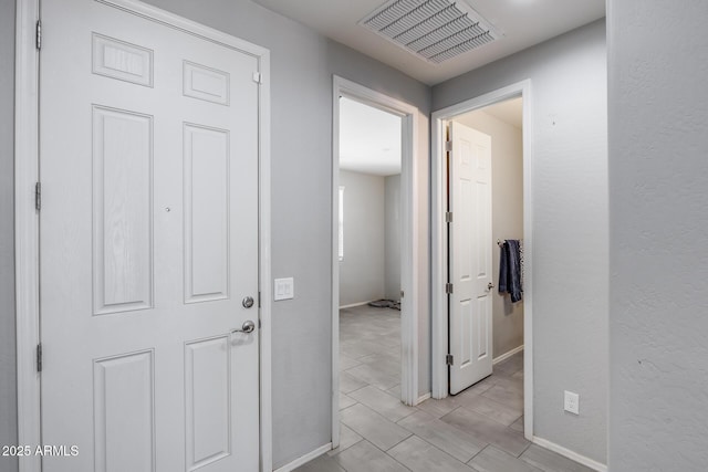 hallway featuring baseboards and visible vents