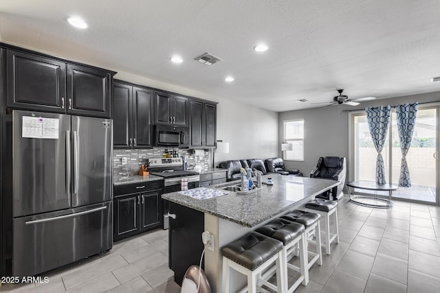 kitchen featuring a breakfast bar area, stainless steel appliances, a sink, and dark cabinetry