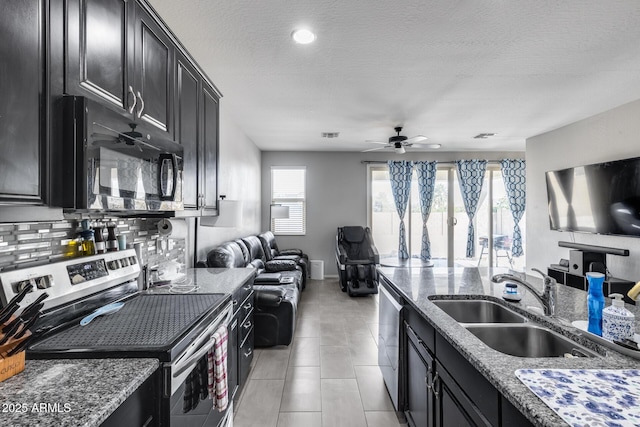 kitchen with open floor plan, stainless steel appliances, dark cabinets, and a sink