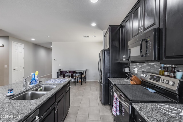 kitchen with stainless steel range with electric cooktop, freestanding refrigerator, dark cabinetry, black microwave, and a sink