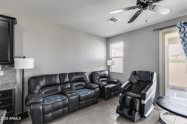 living area with light tile patterned floors, visible vents, and ceiling fan
