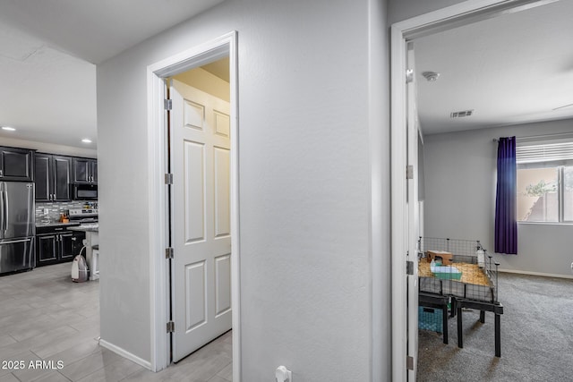 hall featuring baseboards, visible vents, and recessed lighting