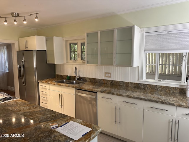 kitchen with appliances with stainless steel finishes, sink, dark stone counters, and white cabinets