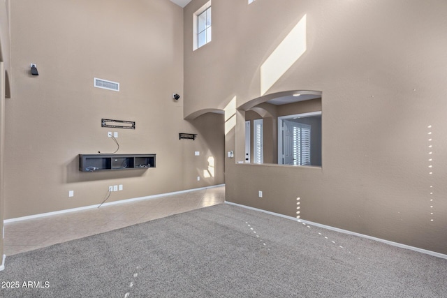 unfurnished living room with tile patterned flooring and a towering ceiling