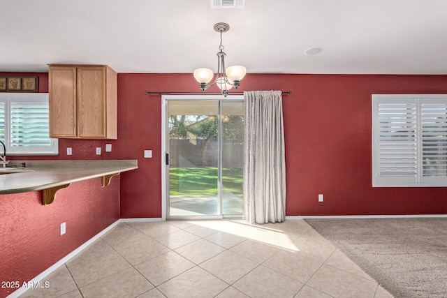 kitchen featuring sink, a notable chandelier, decorative light fixtures, a kitchen bar, and light tile patterned flooring