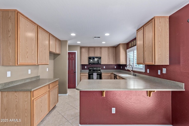 kitchen with black appliances, a kitchen breakfast bar, sink, light brown cabinetry, and kitchen peninsula