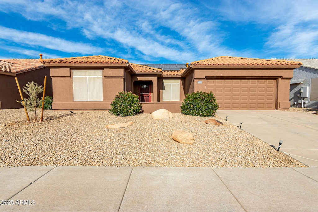 view of front of property featuring a garage and solar panels