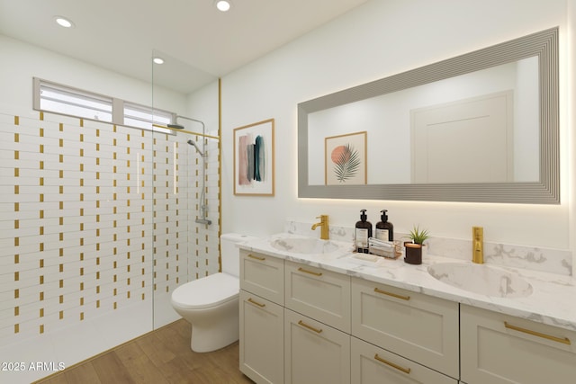 full bath featuring a walk in shower, double vanity, a sink, and toilet