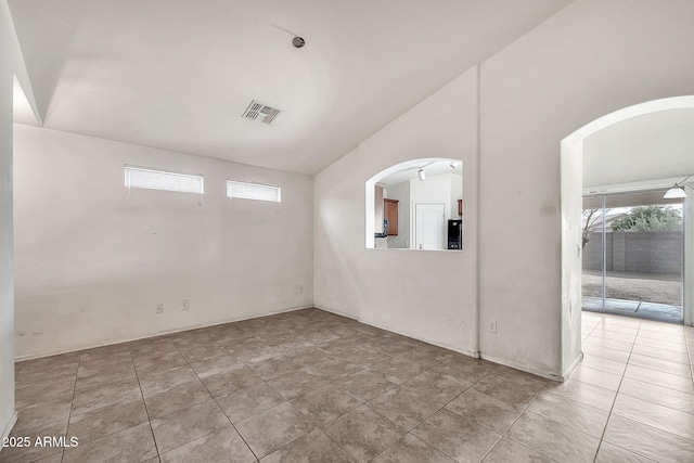 spare room with arched walkways, lofted ceiling, visible vents, and tile patterned floors