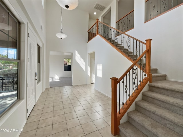 foyer entrance featuring a towering ceiling and light tile patterned floors