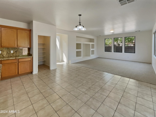 unfurnished living room with light tile patterned floors, built in shelves, and a chandelier