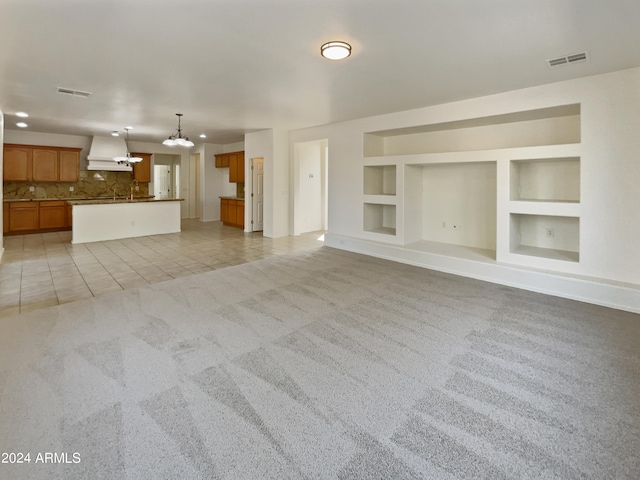 unfurnished living room with light tile patterned flooring, built in features, and a chandelier