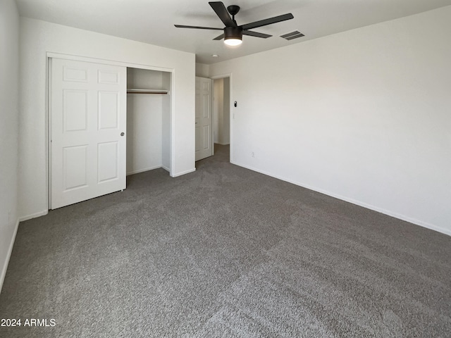 unfurnished bedroom with ceiling fan, a closet, and dark carpet