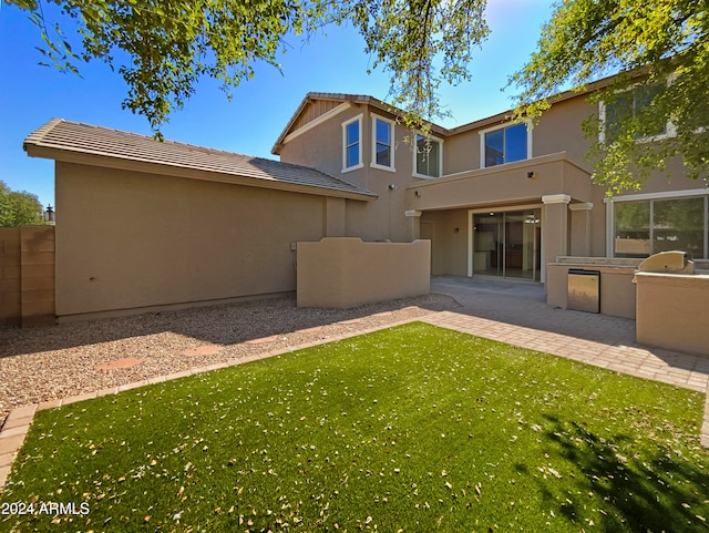 rear view of house featuring area for grilling, a yard, and a patio area