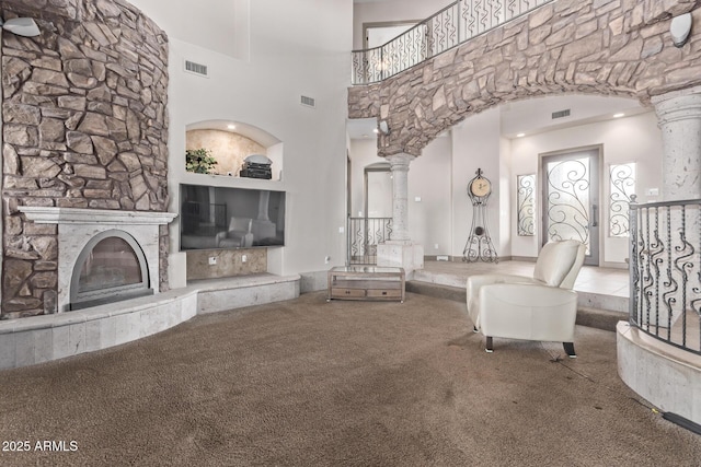 unfurnished living room featuring decorative columns, a towering ceiling, carpet, and a fireplace