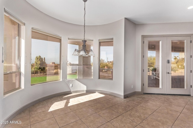 unfurnished dining area with tile patterned floors, a notable chandelier, and french doors