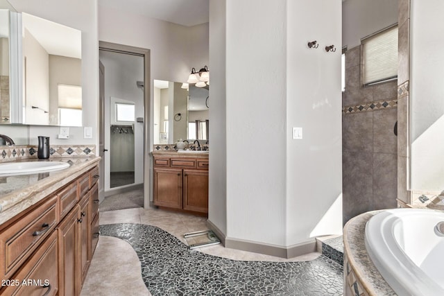 bathroom featuring tiled tub, tile patterned floors, and vanity