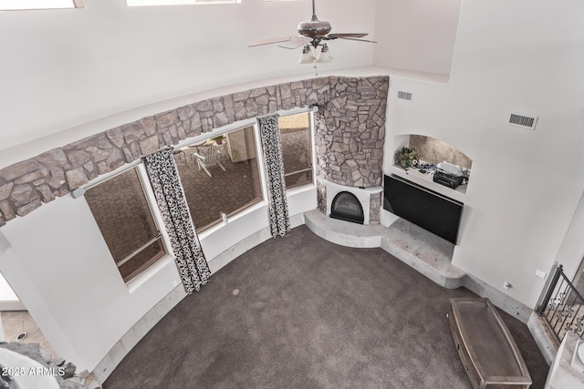 unfurnished living room with ceiling fan and a stone fireplace