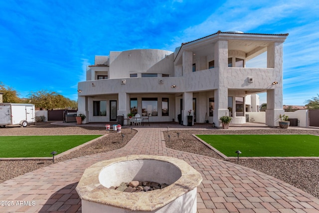 back of house with a balcony, an outdoor fire pit, and a patio