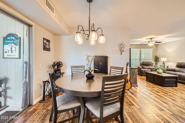 dining space featuring visible vents, light wood finished floors, and ceiling fan with notable chandelier
