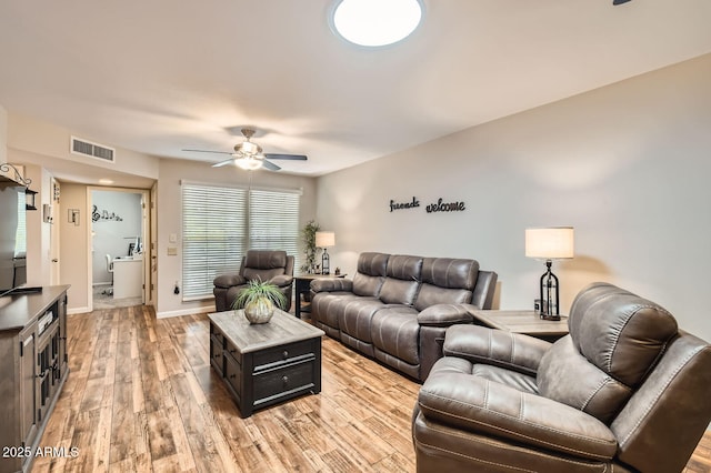 living room featuring baseboards, visible vents, ceiling fan, and light wood-style floors