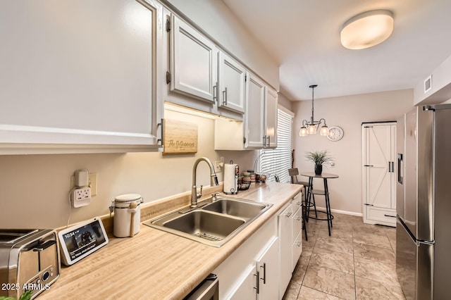 kitchen featuring a toaster, stainless steel fridge, a sink, and light countertops