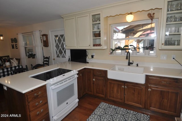 kitchen featuring electric stove, a sink, a peninsula, and light countertops