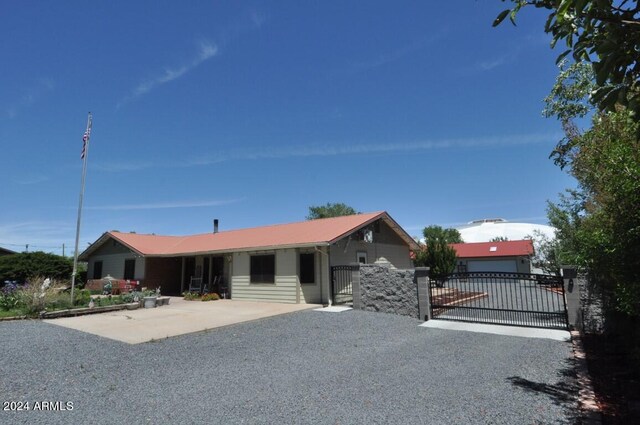 single story home with a gate, gravel driveway, fence, and metal roof