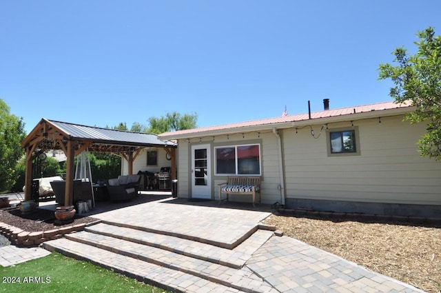 back of property with a gazebo, a patio, metal roof, and an outdoor living space