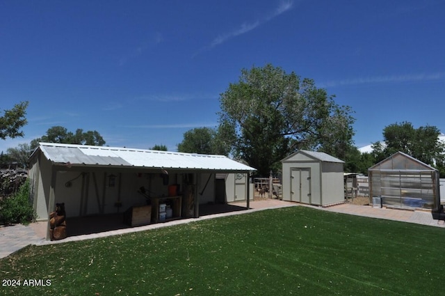 view of grassy yard with an outdoor structure, a greenhouse, and a storage unit