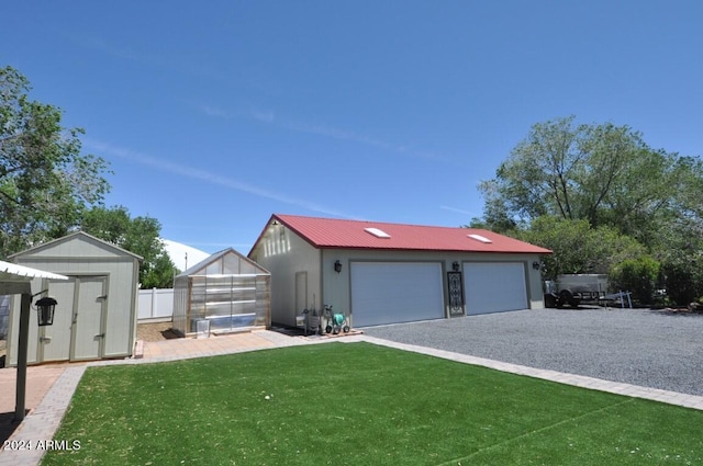 view of front of house with an outdoor structure, a greenhouse, a detached garage, and metal roof