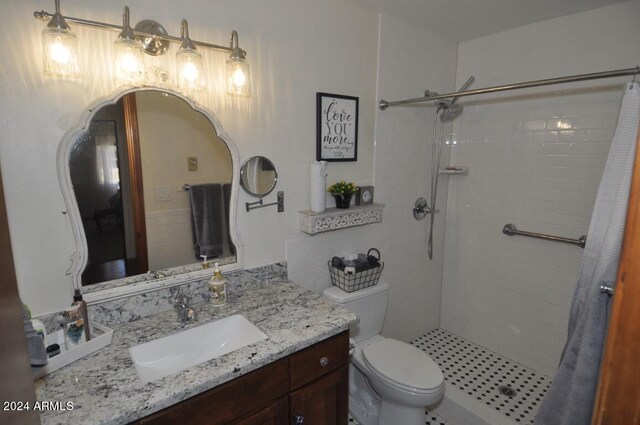 full bathroom with toilet, tiled shower, and vanity