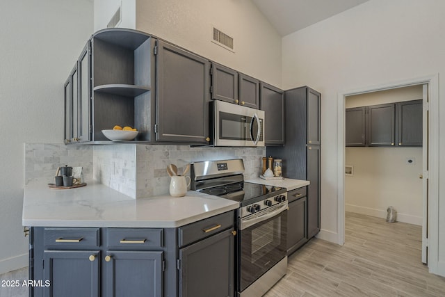4248 E Jason Dr, Phoenix, AZ 85050 - kitchen with stainless steel appliances, tasteful backsplash, open shelves, baseboards, and high vaulted ceiling