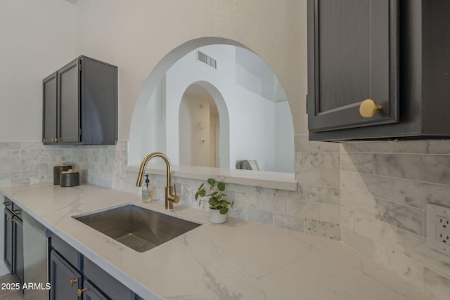 4248 E Jason Dr, Phoenix, AZ 85050 - kitchen featuring a sink, decorative backsplash, light stone countertops, arched walkways, and gray cabinetry