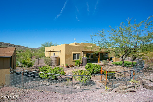 rear view of property featuring a storage unit, a mountain view, and a patio