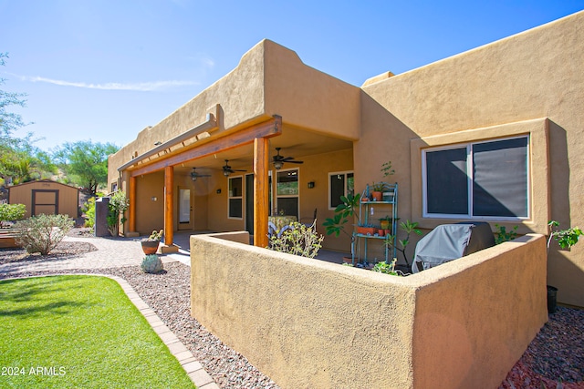 rear view of house with ceiling fan, a shed, and a patio area