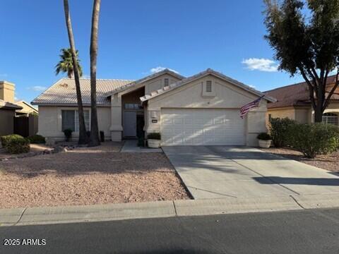 ranch-style home with a garage, concrete driveway, and a tile roof