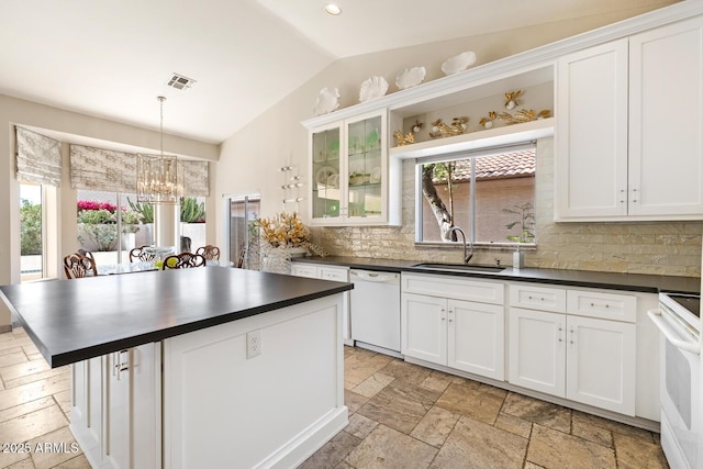 kitchen featuring white appliances, stone tile floors, visible vents, dark countertops, and a sink