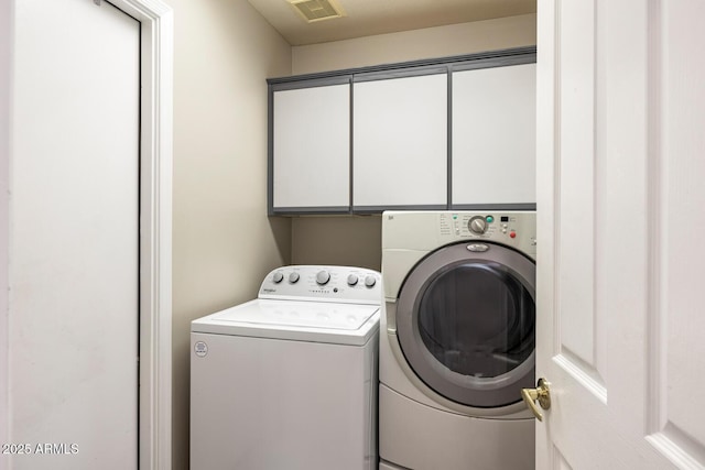 laundry room featuring washer and dryer, cabinet space, and visible vents