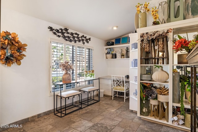 dining area with lofted ceiling, stone tile flooring, and baseboards