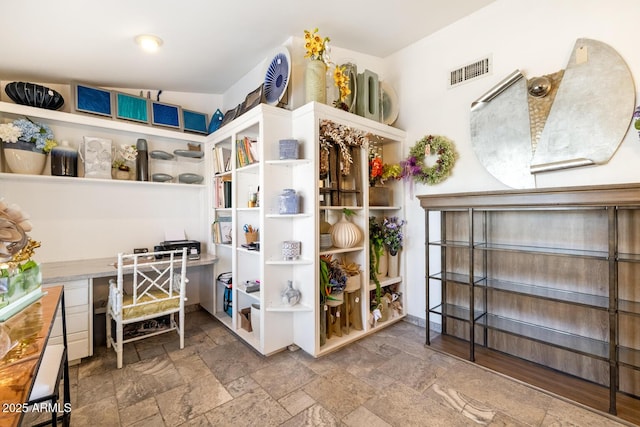 interior space featuring built in study area, visible vents, and stone tile floors